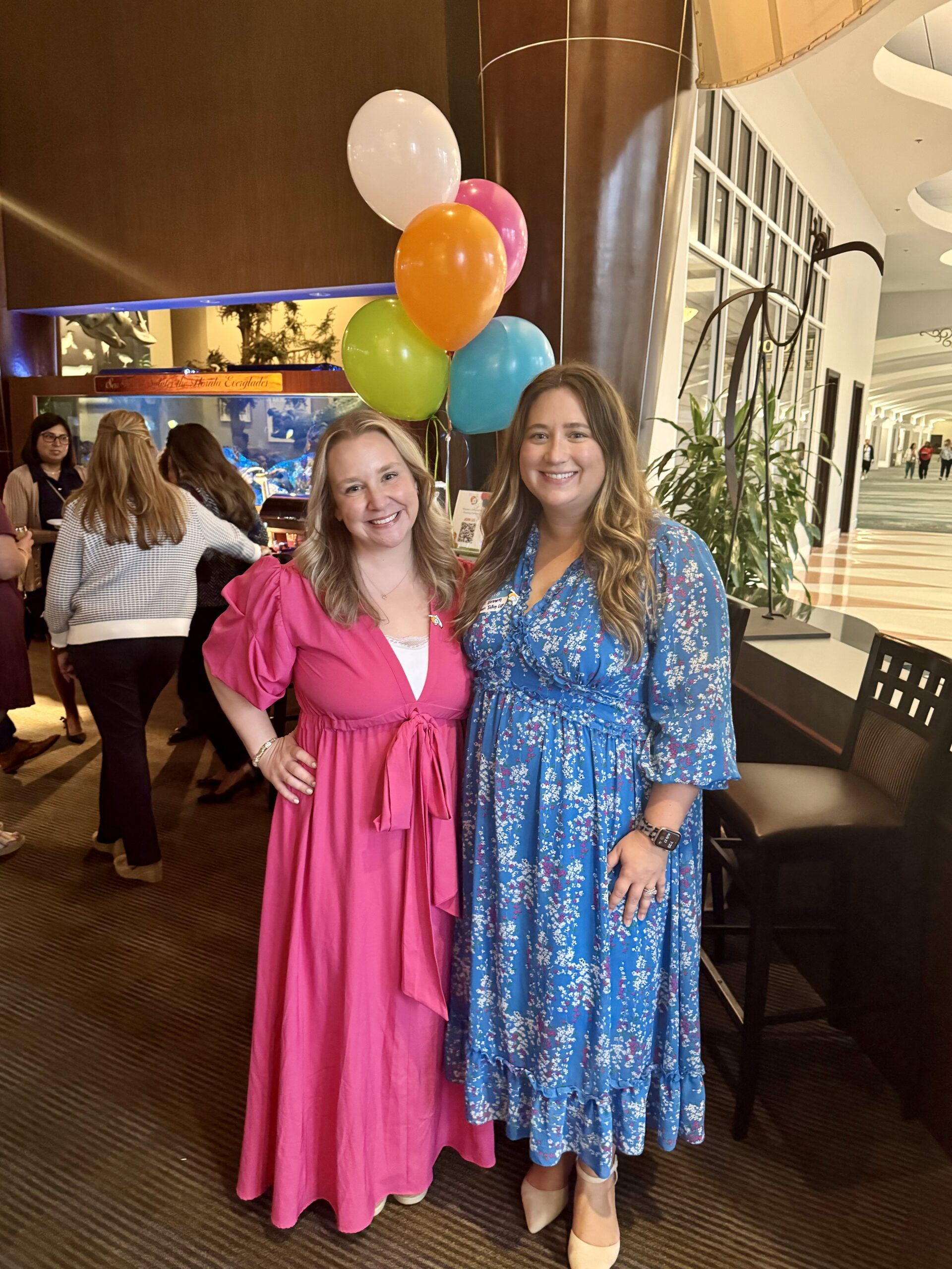 Hannah Anderson in pink dress smiling next to Cassie Brown in Blue